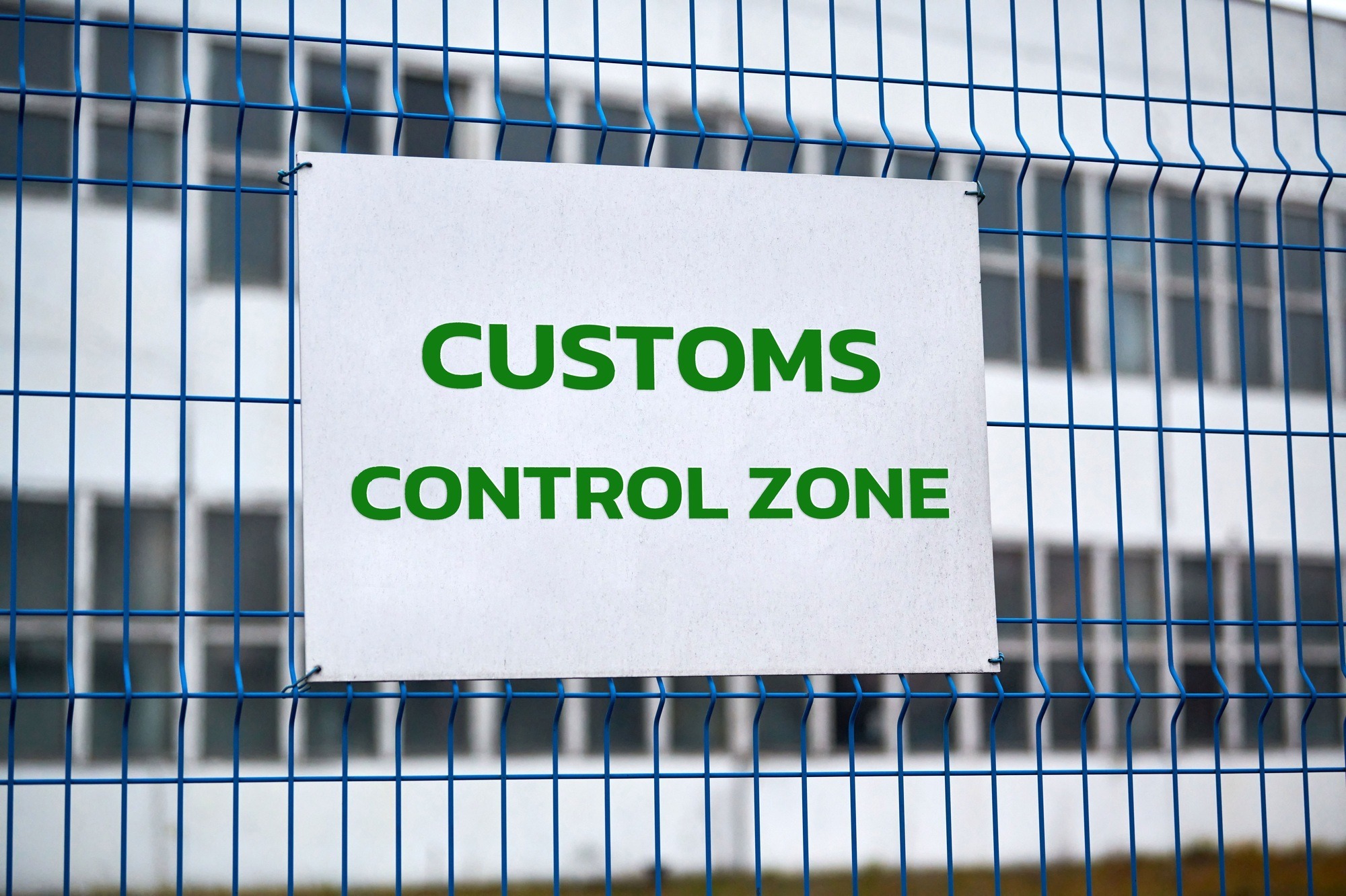 Customs control zone sign on metal fence, border symbol